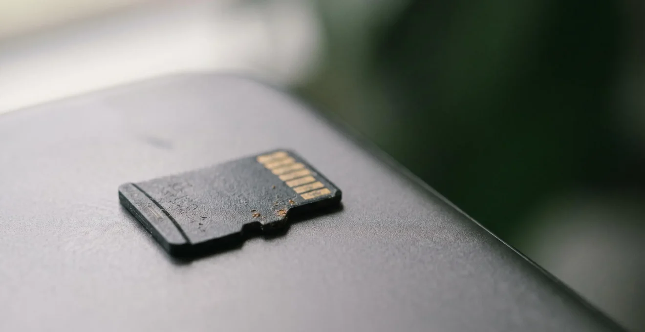 Vue rapprochée d'une carte mémoire microSD posée sur un smartphone moderne avec des reflets de lumière naturelle