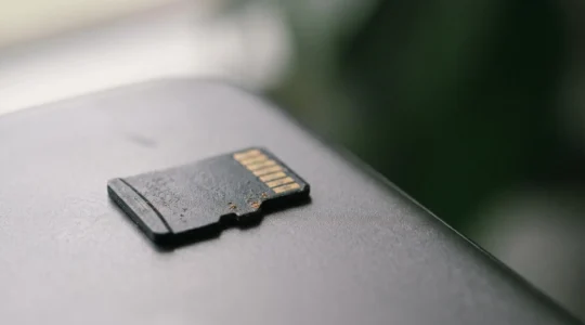 Vue rapprochée d'une carte mémoire microSD posée sur un smartphone moderne avec des reflets de lumière naturelle